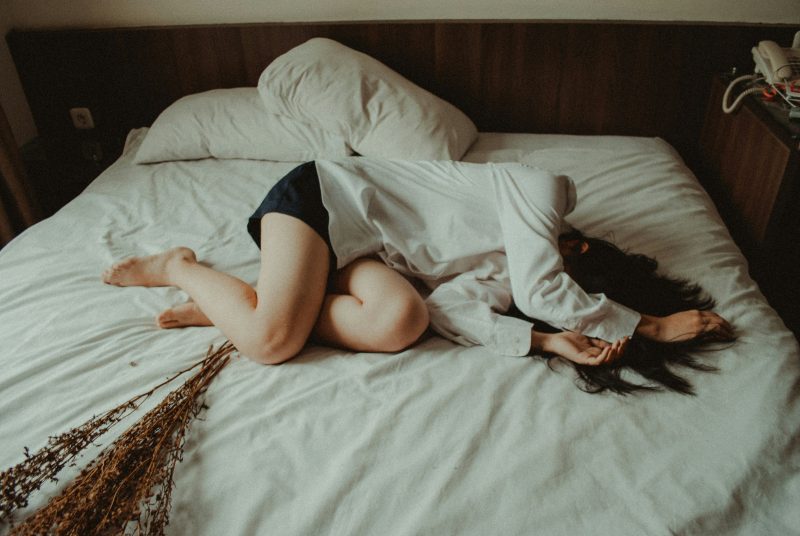 Woman lying in bed looking exhausted and overwhelmed, representing menopause anxiety, depression, and emotional fatigue during hormonal changes.