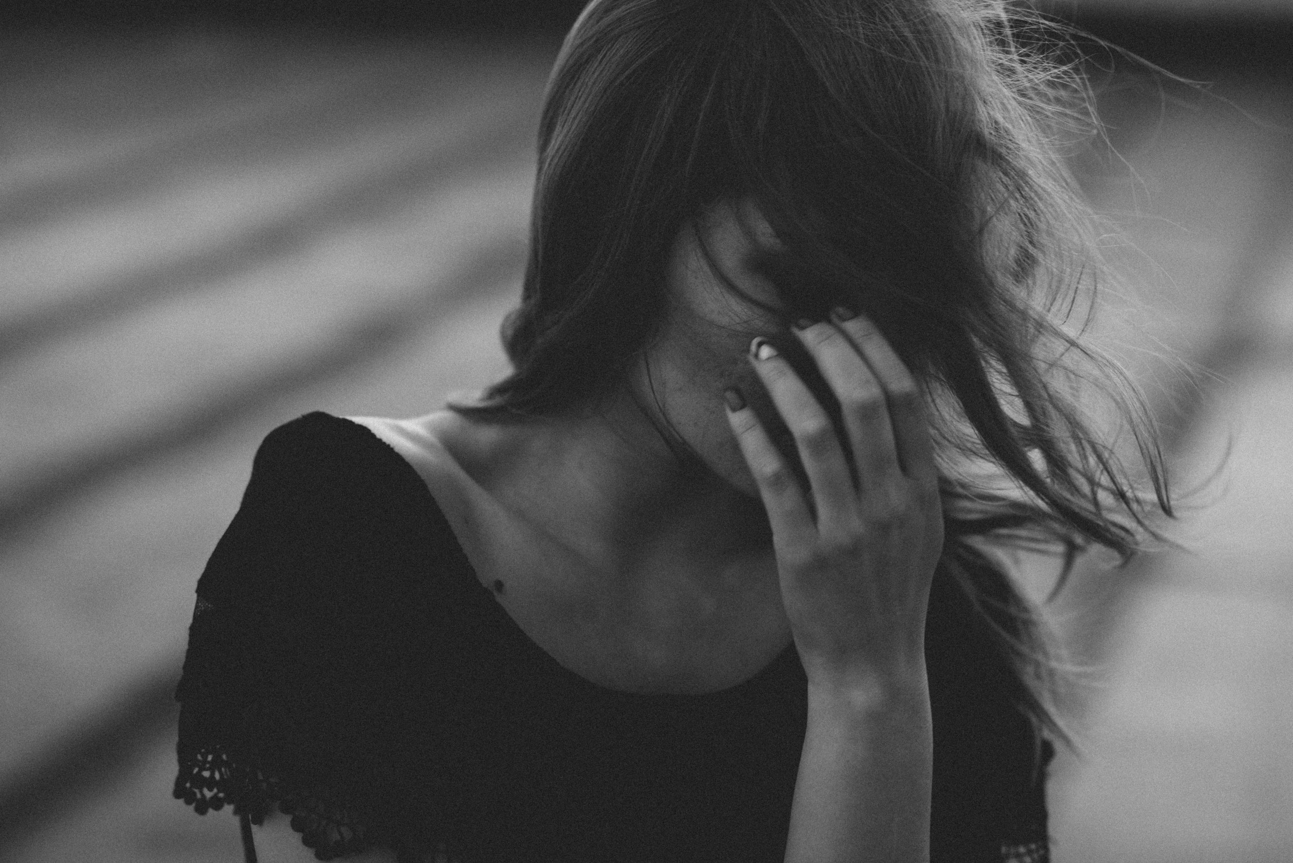 Women experiencing menopause symptoms with hand over face, feeling overwhelmed by hormonal changes and emotional ups and downs.