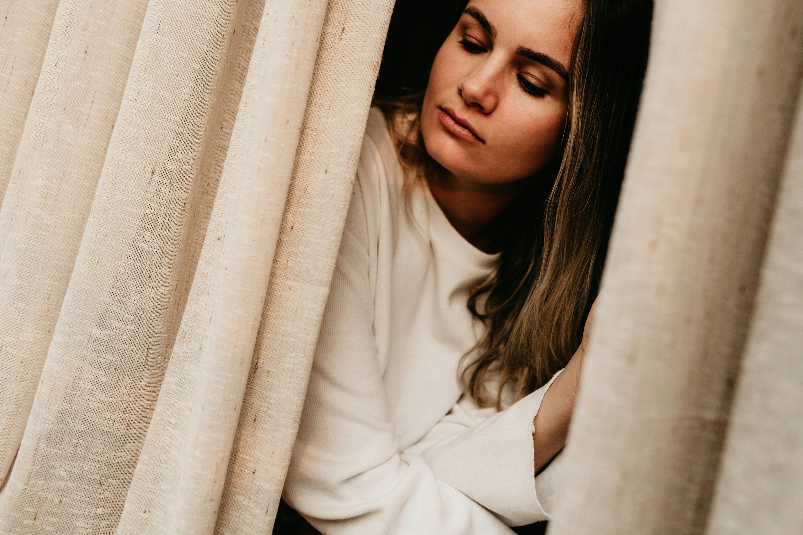 Woman sitting on a bed looking sad and emotional, reflecting depression, low mood, and emotional changes during perimenopause and menopause.